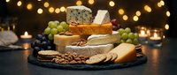 Gourmet cheese platter with crackers, grapes and nuts on dark slate board with warm bokeh lights creating elegant dining atmosphere for entertaining.