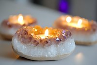 Glowing amethyst crystal candle holders with white quartz base and warm candlelight creating cozy spiritual atmosphere for meditation and home decor.