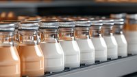Row of glass milk bottles with metal lids on gray shelf, filled with fresh dairy beverage in warm lighting atmosphere, selective focus on foreground bottles.