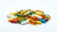 Colorful assorted vitamin pills and capsules scattered on white background for health and wellness supplement designs.