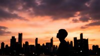 Young professional man silhouette against dramatic sunset city skyline with orange and purple clouds creating inspiring urban business atmosphere.
