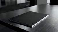 Minimalist black notebook with white pages lying closed on dark wooden desk surface in modern office workspace for business planning and note-taking.