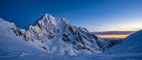 Majestic snow-covered mountain peak at sunset with dramatic alpine landscape, frozen terrain, and clear blue sky. Suitable for travel, nature, and outdoor adventure projects.