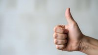 Male hand showing thumbs up gesture against neutral background expressing approval, success and positive feedback for business presentations.