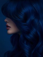Side profile of Asian woman with vibrant dark blue hair styled in waves against deep blue background, showing glossy lips and smooth skin for beauty and hair care advertising.