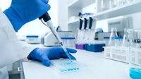 Scientist in blue gloves using pipette for precise liquid handling in modern laboratory with test tubes and equipment for research analysis.