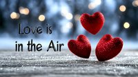 Red glitter hearts on snowy surface with bokeh lights and romantic text overlay, creating dreamy Valentine's Day atmosphere for greeting cards and social media posts.