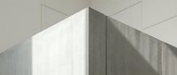 Minimalist concrete wall corner with soft natural light and shadows, showcasing raw texture and modern architectural design in neutral tones.