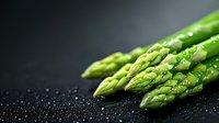 Fresh green asparagus spears with water drops on dark background. Close up macro shot highlighting texture and natural moisture for food photography.