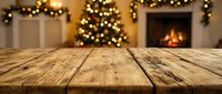 Empty wooden table surface with blurred Christmas tree lights and cozy fireplace in background for holiday product display and festive decorations.