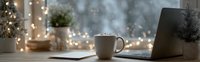 Cozy home office workspace with laptop, coffee mug and warm fairy lights creating comfortable work from home atmosphere for productivity and relaxation.