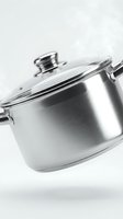 Stainless steel cooking pot with glass lid and handles isolated on white background, ready for kitchen and culinary design use.