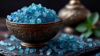 Turquoise blue sea salt crystals in vintage copper bowl on dark stone background, scattered crystals create luxurious spa composition with soft lighting.