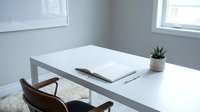 Minimalist workspace with white desk, brown leather chair, open notebook, pen, and small potted plant by bright windows in modern office.