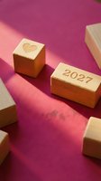 Wooden blocks with heart symbol and 2027 year number arranged on pink fabric background, representing love, future planning, and romantic goals for design and greeting card projects.
