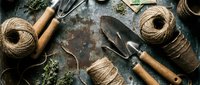 Rustic gardening tools and natural jute twine arranged on weathered wooden surface for organic farming and sustainable agriculture projects.