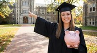 Happy female graduate in cap and gown holding piggy bank on university campus, celebrating education investment and financial planning for future.