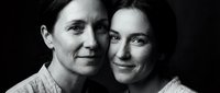 Black and white portrait of mature Caucasian mother and adult daughter embracing, showing generational bond and family love in studio setting.