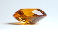 Brilliant cut citrine gemstone with faceted surface reflecting warm amber light on white background, showcasing luxury jewelry element for design projects.