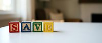 Colorful wooden alphabet blocks spelling SAVE on a white table, symbolizing financial savings, budgeting, and money management concepts.