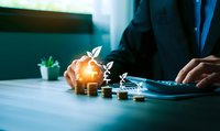 Businessman calculating investment growth with glowing plant sprouting from coins stack on desk. Financial planning and sustainable business development concept.