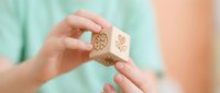 Close-up of hands holding wooden blocks with leaf and gear icons, representing eco-friendly business solutions and sustainable growth for corporate design projects.