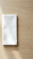 White linen napkin folded on light wood surface, ready for dining, hospitality, restaurant, or event design mockups.