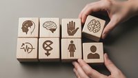 Hands arranging wooden blocks with mental health and psychology icons including brain, person, and medical symbols for wellness concepts.
