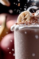 Creamy chocolate milkshake topped with whipped cream and cocoa powder splashing in motion against dark background, macro shot capturing flying droplets and garnish.
