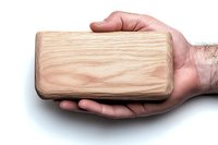 Male hand holding large wooden block against white background, showcasing natural wood grain texture and craftsmanship. Isolated object for design projects.