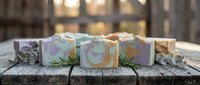 Handmade artisan soap bars with natural ingredients displayed on rustic wooden surface with soft bokeh lighting for spa and wellness concepts.