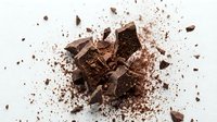 Crushed chocolate pieces and cocoa powder scattered on white background, suitable for food photography, baking content, and culinary design projects.