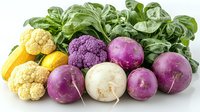 Fresh colorful vegetables on white background including yellow cauliflower, purple cauliflower, turnips and green basil leaves arranged in decorative composition.