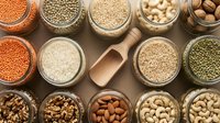 Assorted legumes, grains, nuts and seeds in wooden bowls on rustic background. Healthy organic food ingredients for cooking and nutrition.