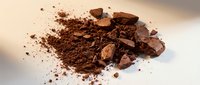 Crushed cocoa powder and chocolate chunks scattered on white surface, ideal for baking, confectionery, and culinary content.
