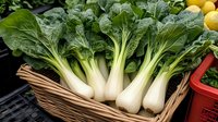 Fresh bok choy with white stems and dark green leaves arranged in wicker basket alongside citrus fruits, displaying farm fresh produce for healthy eating.