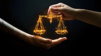 Glowing golden scales of justice between light and dark hands against black background symbolize equality, law, and balance in legal system.