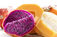 Fresh dragon fruit slices showing vibrant purple flesh with black seeds next to yellow dragon fruit pieces on white background, macro food photography.