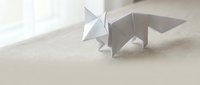 Origami paper fox standing on a soft beige surface in natural light, showcasing minimalist Japanese paper folding art and craft.