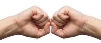 Two clenched fists facing each other in confrontational gesture on white background. Conflict resolution, teamwork, unity, strength concept.