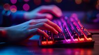 Hands typing on illuminated gaming keyboard with vibrant neon pink and blue lighting effects. Perfect for esports, gaming setup, or technology lifestyle content background.