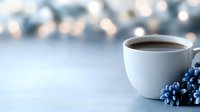 White coffee cup with fresh blueberries on light surface with soft bokeh background for morning breakfast and healthy lifestyle concepts.