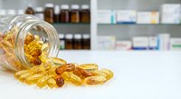 Omega-3 fish oil capsules spilling from glass jar on pharmacy counter with medicine bottles and healthcare products in background for wellness supplements.