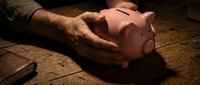Elderly hands protecting pink piggy bank on rustic wooden table symbolizing retirement savings security and financial planning for senior citizens.