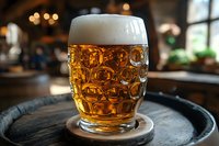 Fresh draft beer with thick foam head in traditional dimpled glass mug on wooden table in pub, golden bubbles and bokeh lights in background.