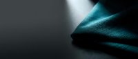 Elegant teal fabric with soft folds and dramatic lighting creates sophisticated textile background for luxury fashion and interior design projects.
