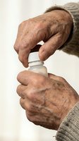 Senior male hands opening medication bottle with white cap, showing aged skin texture and wrinkles. Healthcare and pharmaceutical concept for elderly care, prescription drugs, and wellness.