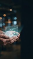 Hands holding futuristic holographic display with data analytics and sustainability metrics against blurred city lights background for business technology concepts.