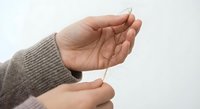 Woman hands in knit sweater holding delicate white feather on clean background for mindfulness meditation and spiritual wellness concepts.