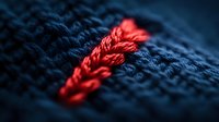 Red thread stitched into dark blue denim fabric creates striking contrast in extreme macro photography, highlighting detailed textile texture and craftsmanship.